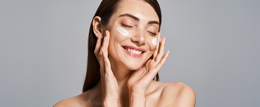 Młoda kobieta stosująca krem z ceramidami na twarz