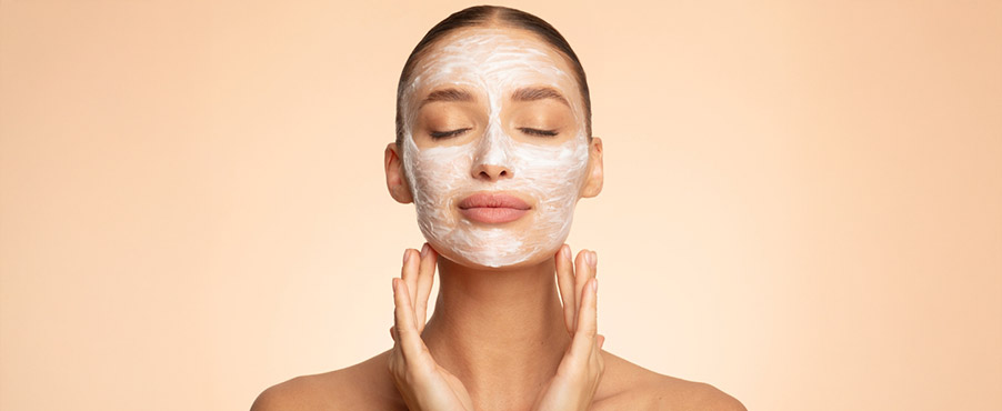 Młoda kobieta z kosmetykiem pielęgnacyjnym nałożonym na całą twarz